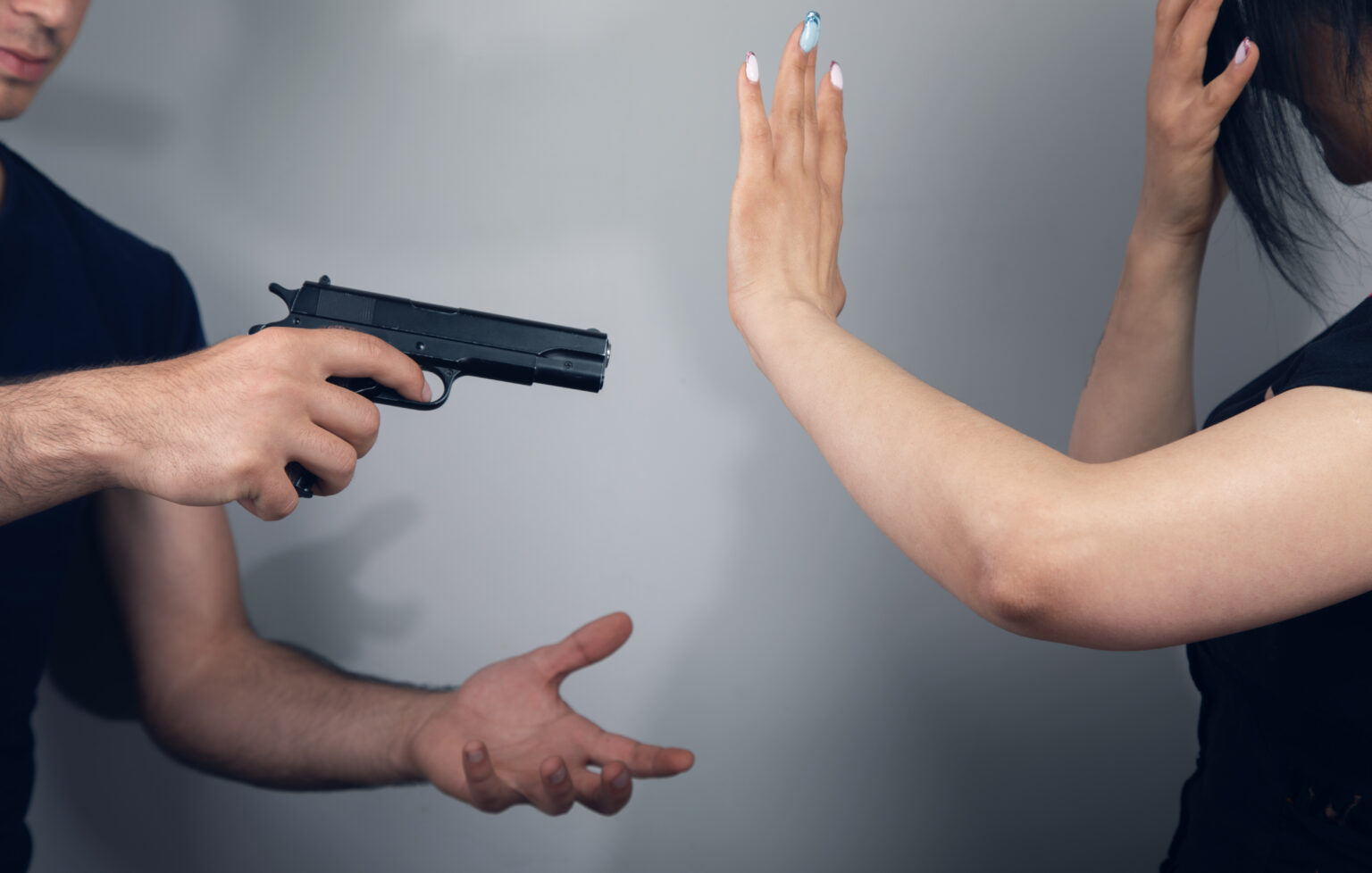 man holding the next person at gunpoint