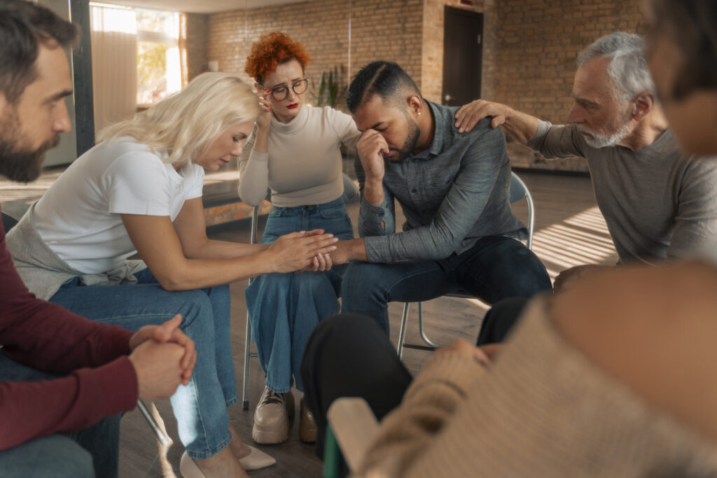 Group therapy session focusing on emotional support, individuals expressing vulnerability and connection, addressing family conflict and stress related to election issues.