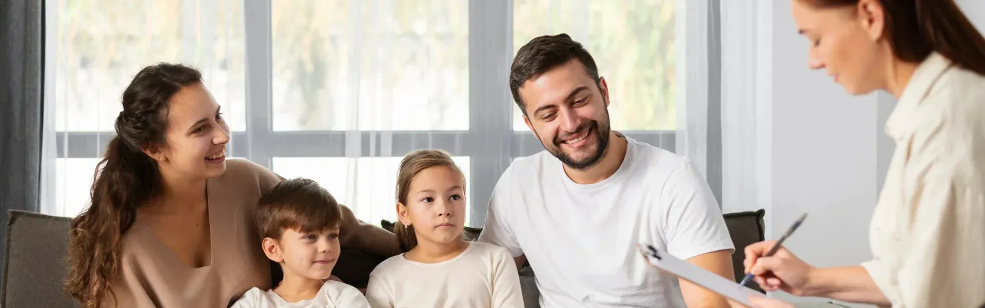 Family therapy session with a therapist and a family of four, discussing mental health and counseling in a comfortable setting.